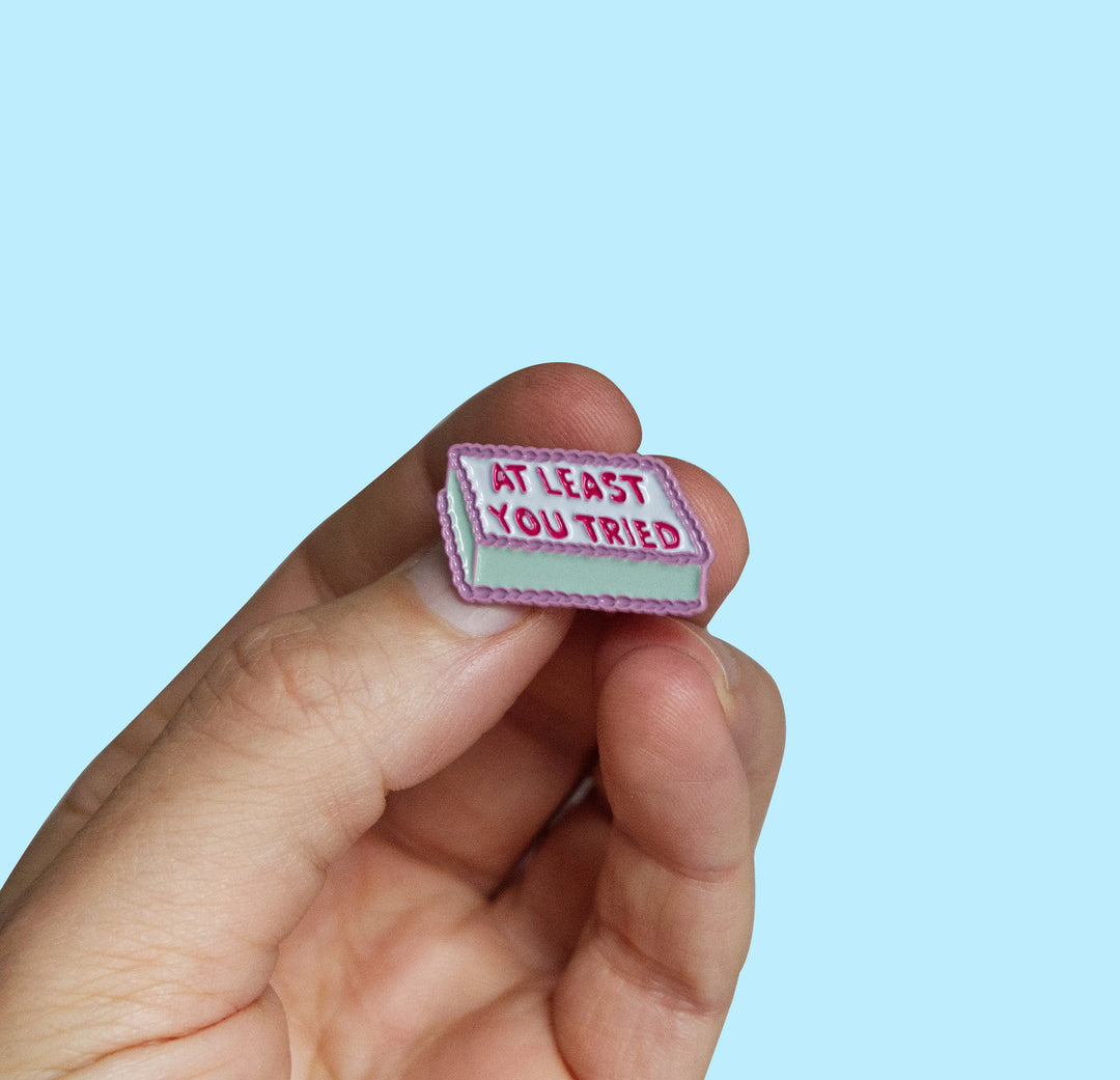 A hand holding a small rectangular patch with the text &