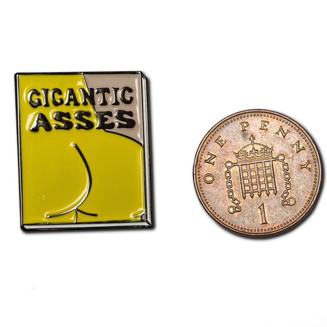 Gigantic Asses enamel Pin next to penny for size
