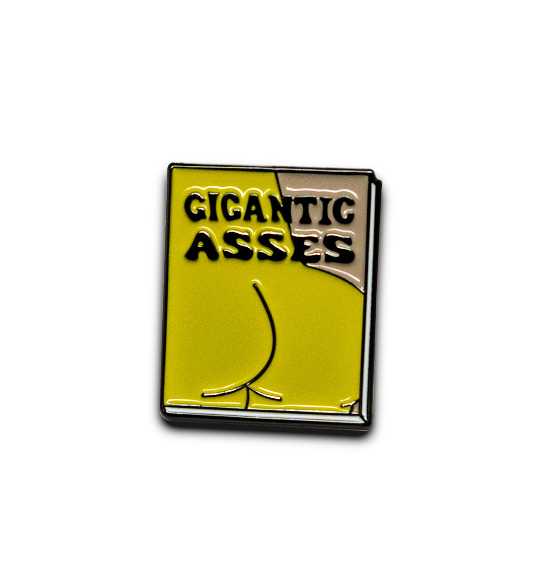 A novelty enamel pin shaped like a book with the text &